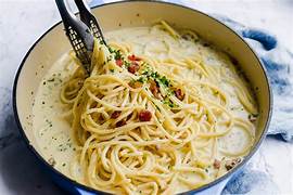 Plate of creamy garlic butter spaghetti garnished with fresh parsley and cracked black pepper, served with a fork on the side.