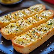 Slices of golden, crispy garlic bread loaded with melted cheese and herbs, served warm on a rustic plate.