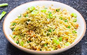 A bowl of colorful veg fried rice with carrots, peas, and spring onions, served hot in a black ceramic bowl.