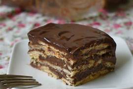 Layers of chocolate pudding and biscuit stacked in a glass dish, topped with chocolate shavings and a cherry.